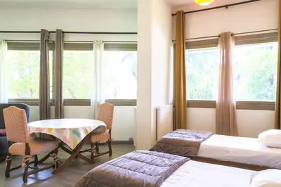 a room with two beds and a table and chairs at ACCI Cannes Gallia in Cannes