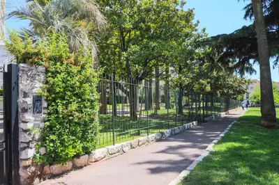 a fence in a park with trees and a sidewalk at ACCI Cannes Gallia in Cannes