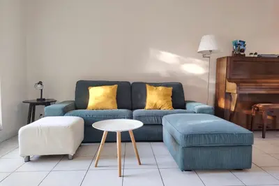 a living room with a blue couch and a piano at Charming & bright flat with AC Garden 300m and Closed Garage - BENAKEY in Cannes