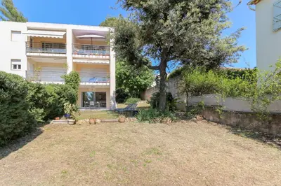 a building with a tree in front of a yard at Charming & bright flat with AC Garden 300m and Closed Garage - BENAKEY in Cannes