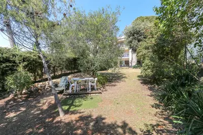 a garden with a table and trees in front of a building at Charming & bright flat with AC Garden 300m and Closed Garage - BENAKEY in Cannes