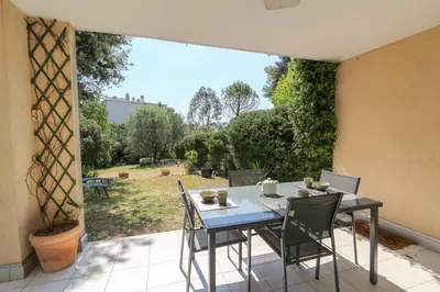 a table and chairs on a patio with a view of a yard at Charming & bright flat with AC Garden 300m and Closed Garage - BENAKEY in Cannes