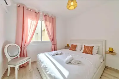 a bedroom with a white bed with a chair and a window at Agréable 3pièces Cannes Croisette in Cannes