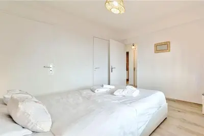 a white bedroom with a large white bed with two pillows at Agréable 3pièces Cannes Croisette in Cannes