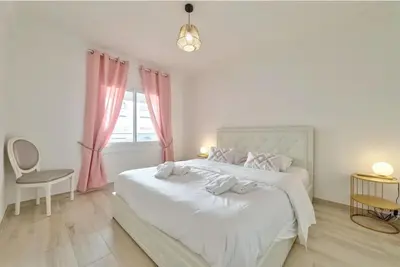 a white bedroom with a large white bed with pink curtains at Agréable 3pièces Cannes Croisette in Cannes
