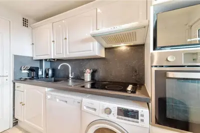a kitchen with white cabinets and a washer and dryer at Agréable 3pièces Cannes Croisette in Cannes