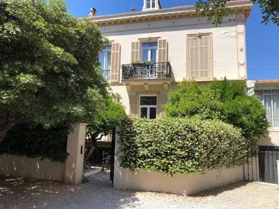 a large white house with a fence and bushes at MARIE ANTOINETTE in Cannes