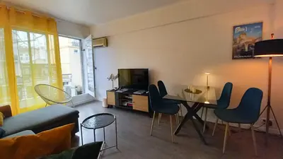a living room with a table and chairs and a television at Palais Carnot central apartment with balcony and A C in Cannes
