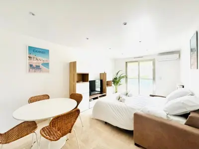 a white bedroom with a bed and a table and chairs at CannesAzur - Appartement Terrasse centre Cannes in Cannes