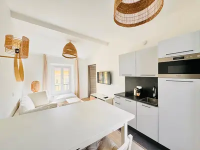 a kitchen with white cabinets and a white table at Le Bohème - Logement Cozy centre in Cannes