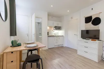 a kitchen with white cabinets and a table and chairs at Studio Alexandre - Cannes in Cannes