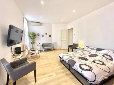 a bedroom with a large bed and a tv in it at Woody old town appartement by Welcome to Cannes in Cannes