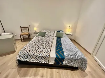 a bed with a comforter and a chair in a room at Woody old town appartement by Welcome to Cannes in Cannes