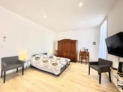 a bedroom with a bed and two chairs and a television at Woody old town appartement by Welcome to Cannes in Cannes