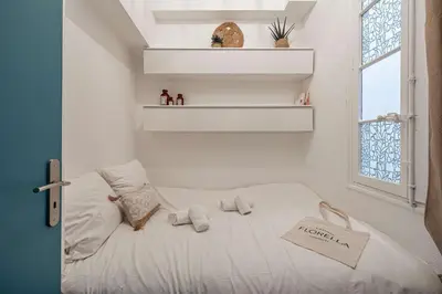 a small bedroom with a white bed with a window at LA PERLE au cœur du centre ville, idéal pour séjours loisirs ou business in Cannes