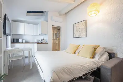 a small bedroom with a bed and a kitchen at Joli studio Cannes marché forville in Cannes
