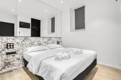 a bedroom with a large bed with white sheets at 2 Chambre Modern - Proche palais - Spacieux - Calme in Cannes