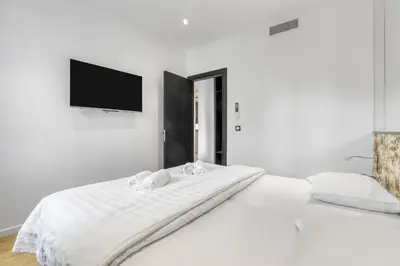 a bedroom with a white bed with a flat screen tv at 2 Chambre Modern - Proche palais - Spacieux - Calme in Cannes