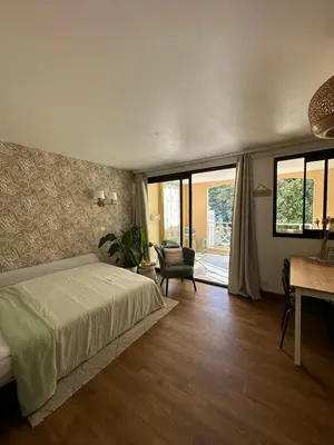a bedroom with a bed and a chair and windows at Villa Francia Cannes in Cannes