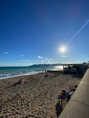 a beach with people sitting on the sand and the ocean at Villa Francia Cannes in Cannes