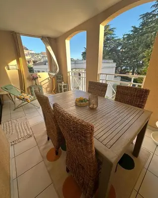 a wooden table and chairs in a room with windows at Villa Francia Cannes in Cannes