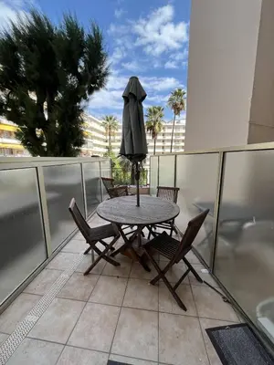 a table and chairs on a balcony with an umbrella at Cannes Croisette - PALAIS MIRAMAR - Studio au calme avec terrasse in Cannes