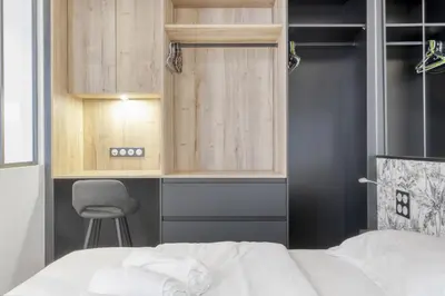 a bedroom with a bed and a chair and cabinets at 1 Chambre Modern L- Calme - Hypercentre à 2 minutes du Palais in Cannes