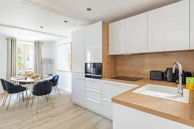 a kitchen with white cabinets and a table with chairs at 15 RIOUFFE - Splendide appartement 6 couchages à 50m à pieds du Palais in Cannes