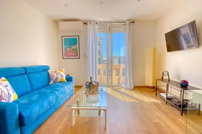 a living room with a blue couch and a table at Cannes Croisette - 4 Personnes - Vue mer in Cannes
