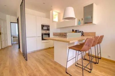 a kitchen with white cabinets and a counter with stools at Cannes Croisette - 4 Personnes - Vue mer in Cannes
