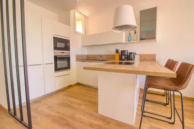 a kitchen with white cabinets and a counter with chairs at Cannes Croisette - 4 Personnes - Vue mer in Cannes