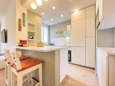 a kitchen with white cabinets and a counter with a stool at Le Palm by Winsome Destination in Cannes