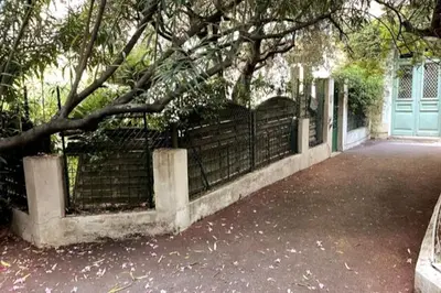 a fence with a tree in front of a house at Augusta Palace - T3 **** 74m² - 150m Croisette in Cannes