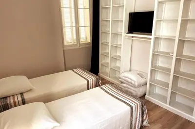 a room with two beds and a tv and shelves at Augusta Palace - T3 **** 74m² - 150m Croisette in Cannes