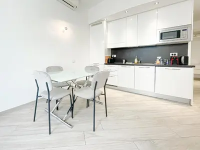 a kitchen with white cabinets and a table and chairs at Tony Allard By Winsome Destination 2E in Cannes