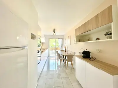 a kitchen and dining room with white cabinets and a table at Vezelay 3 luxury 3 bedrooms, by Welcome to Cannes in Cannes