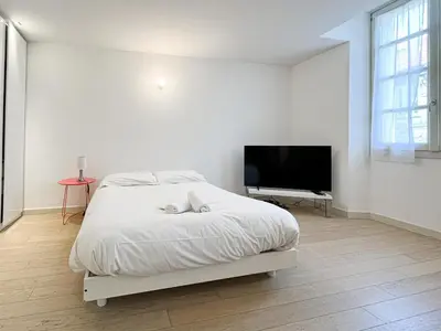 a white bedroom with a bed and a flat screen tv at Tony Allard By Winsome Destination 3F in Cannes