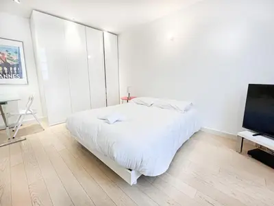 a white bedroom with a bed and a flat screen tv at Tony Allard By Winsome Destination 3F in Cannes