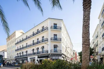 a white building with balconies and a palm tree at Crisol Lumière in Cannes