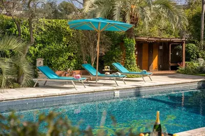 two chairs and an umbrella next to a swimming pool at Cannes centre maison bourgeoise in Cannes