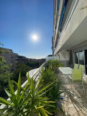 a balcony of a building with green chairs and plants at 3 Pièces avec grande terrasse in Cannes