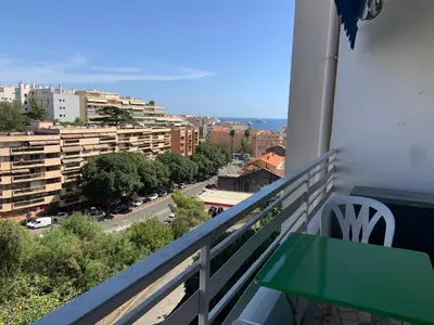 a balcony with a green table and a street at T2 à proximité des plages in Cannes