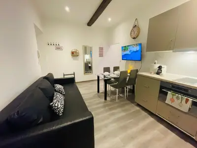 a living room with a black couch and a kitchen at APRT Cannes Beach Festival ARNESE in Cannes