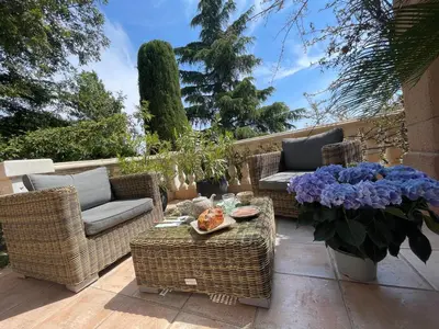 a patio with wicker chairs and a table and flowers at Carolienne in Vallauris