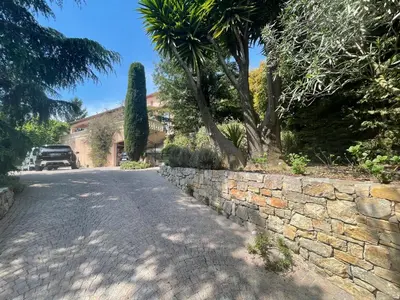 a stone road with a stone wall and trees at Carolienne in Vallauris