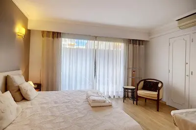 a bedroom with a large bed with a chair and a window at 2 bdr apartment with garden next to the Croisette in Cannes