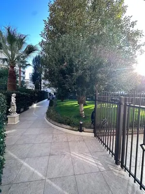 a wrought iron fence next to a sidewalk with trees at Superbe Studio avec balcon Rue d’Antibes in Cannes