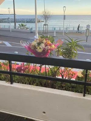 a bowl of flowers sitting on a railing near the beach at Appartement Front de mer à Cannes -Vue Mer & Terrasse in Cannes