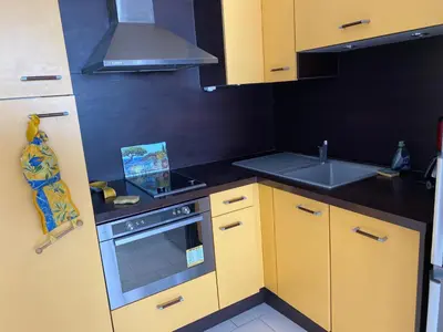 a small kitchen with yellow cabinets and a sink at Appartement Front de mer à Cannes -Vue Mer & Terrasse in Cannes