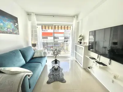 a living room with a blue couch and a tv at Colony 2 in Cannes